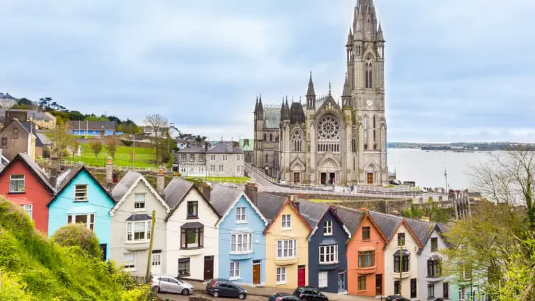 Colorful row of houses with the towering St. Colman's Cathedral in the background, in the port town of Cobh near Cork City, Ireland